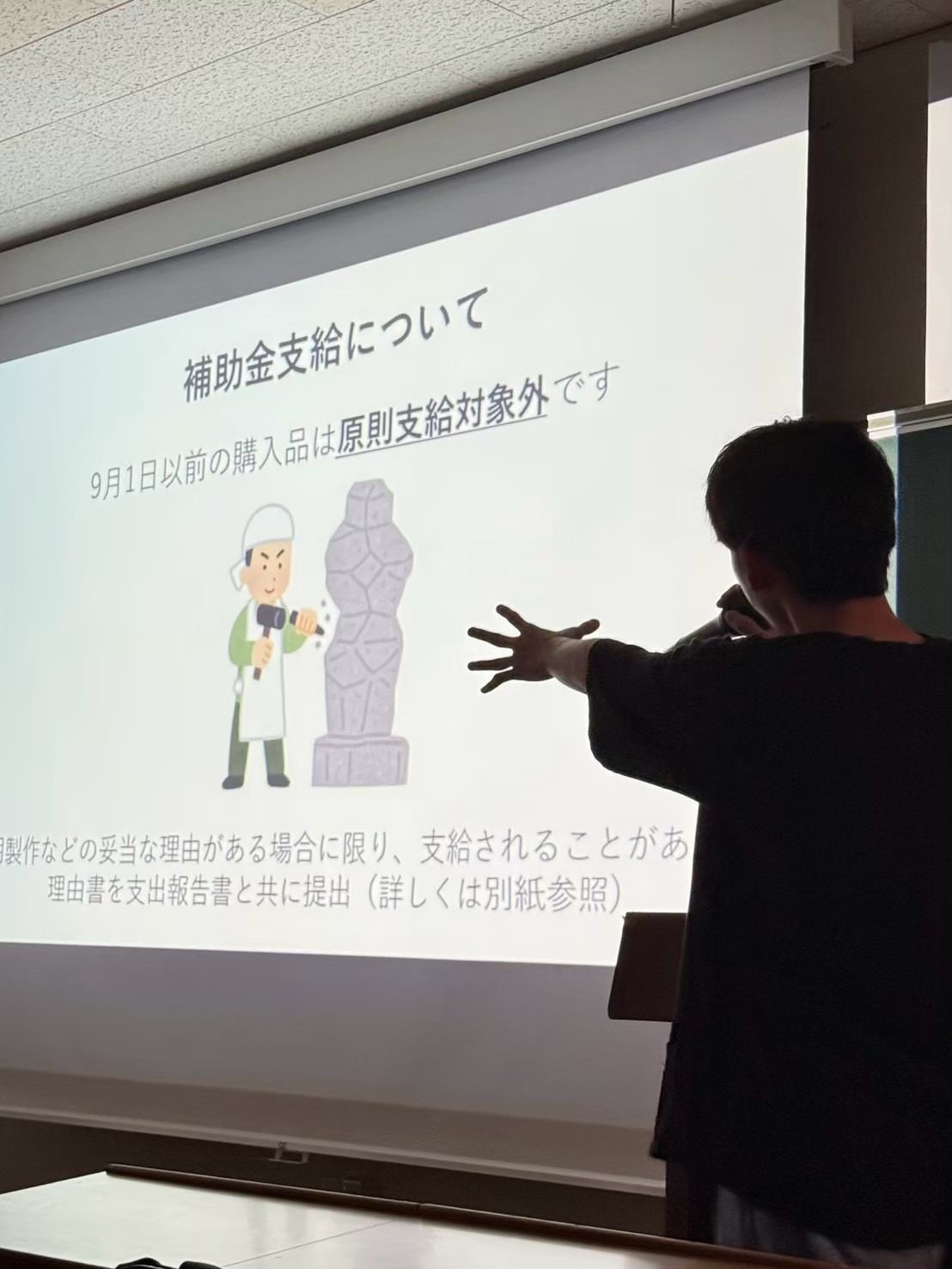 「補助金支給について 9月1日以前の購入品は原則支給対象外です」と映したスライドを指しながら説明する実行委員