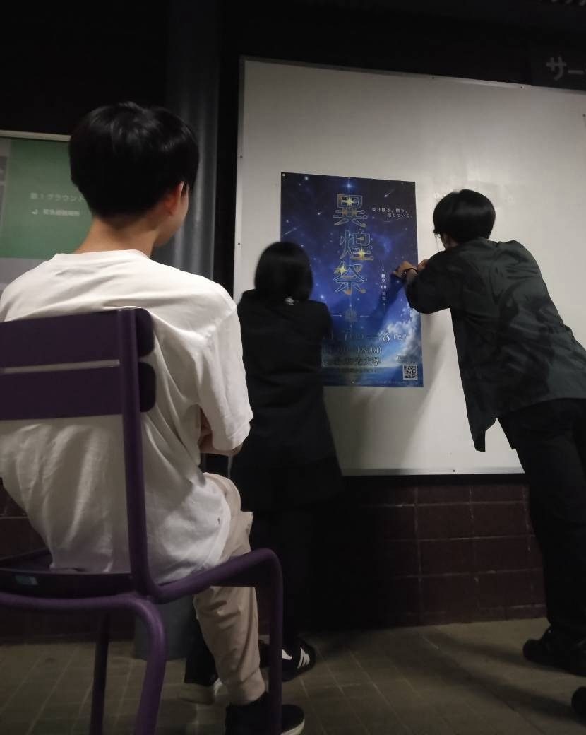 掲示板に異煌祭 2026 のポスターを貼る実行委員