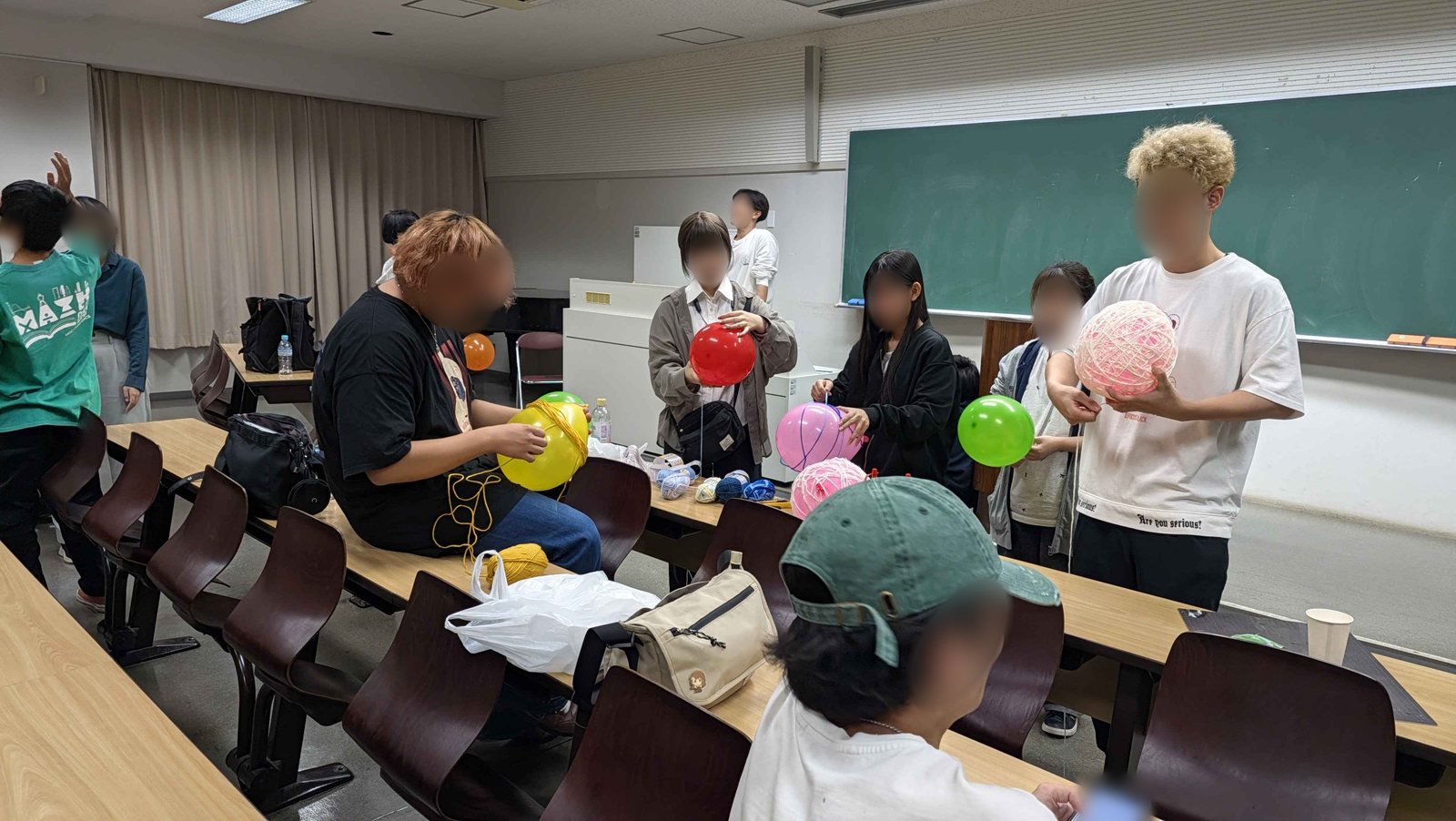 赤・ピンク・緑・黄色の風船や毛糸の飾りを手に、教室で作業する実行委員